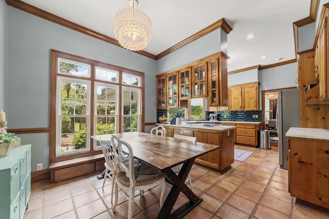 kitchen with an inviting chandelier, appliances with stainless steel finishes, backsplash, ornamental molding, and pendant lighting