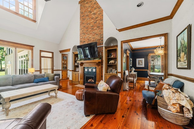 living room featuring high vaulted ceiling, hardwood / wood-style floors, an inviting chandelier, and a large fireplace