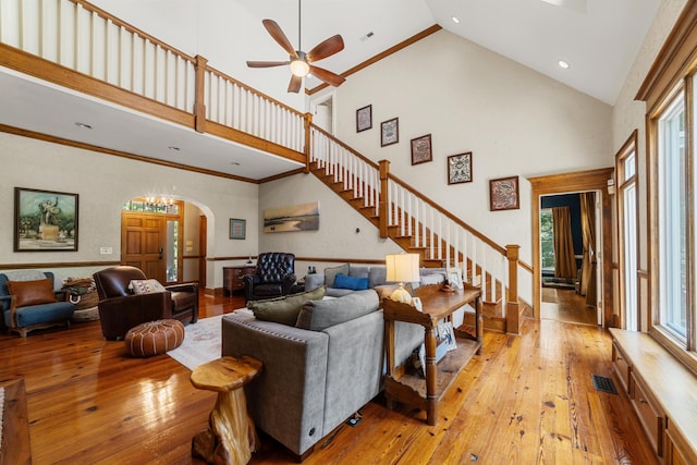 living room with ceiling fan, light hardwood / wood-style floors, and a towering ceiling