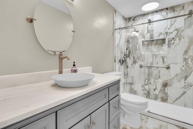 bathroom featuring marble finish floor, vanity, a marble finish shower, and toilet