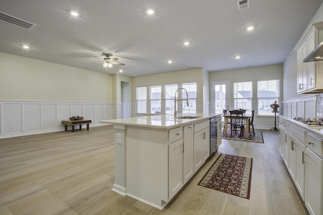 kitchen with a center island with sink, white cabinetry, light hardwood / wood-style floors, and sink