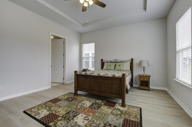 bedroom featuring a tray ceiling, ceiling fan, and light hardwood / wood-style floors