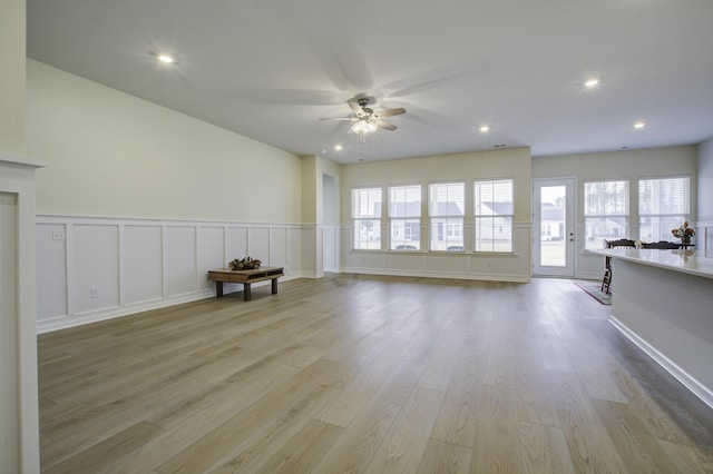 unfurnished living room with light wood-type flooring, plenty of natural light, and ceiling fan