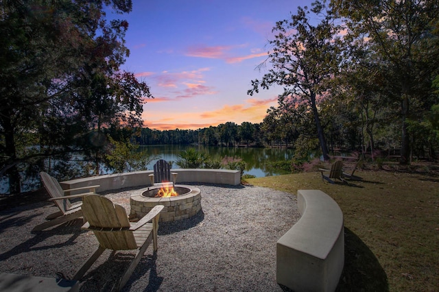 patio terrace at dusk featuring a water view and an outdoor fire pit