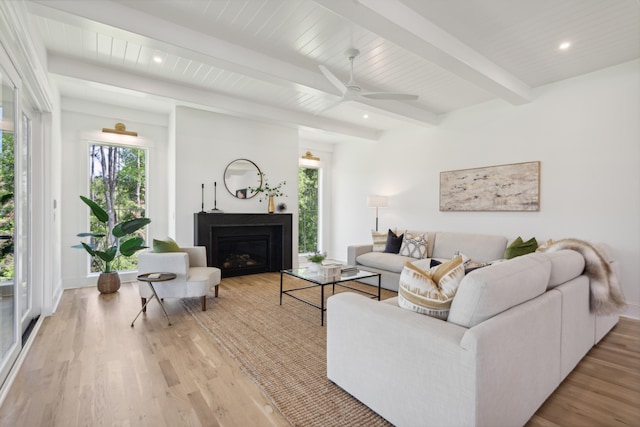 living room featuring beam ceiling, ceiling fan, and light wood-type flooring