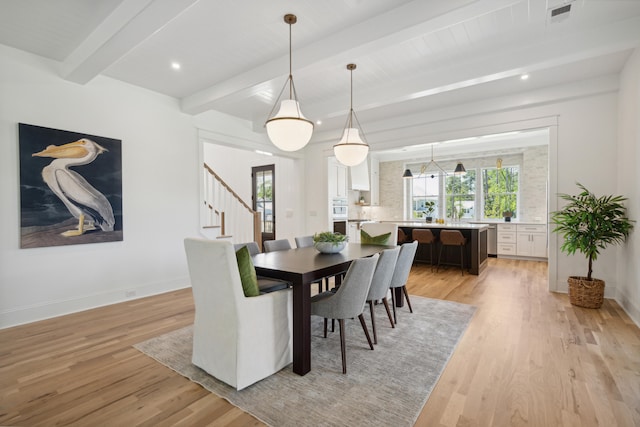 dining area featuring beam ceiling and light wood-type flooring