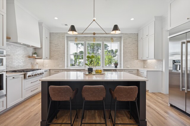 kitchen featuring stainless steel appliances, a kitchen breakfast bar, light countertops, and custom range hood