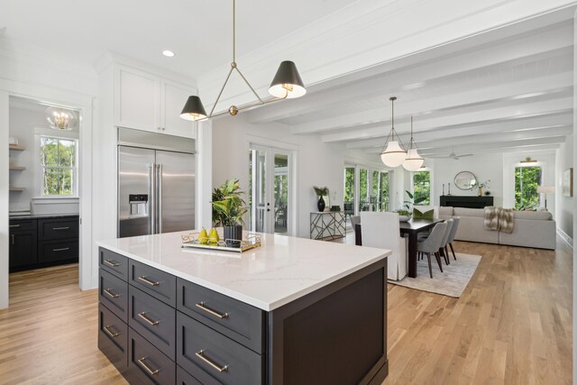 kitchen featuring beamed ceiling, a center island, white cabinetry, stainless steel built in refrigerator, and light hardwood / wood-style flooring