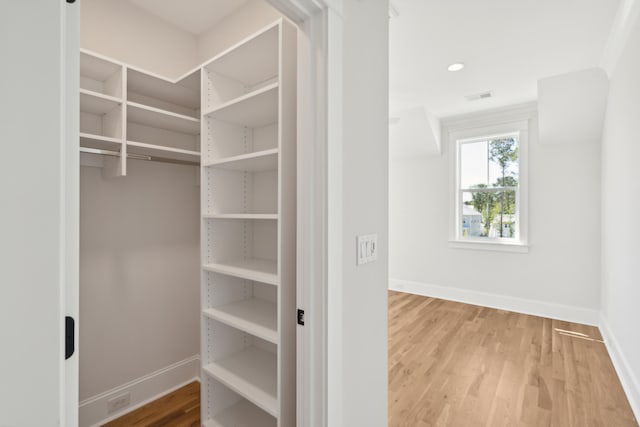 walk in closet with light hardwood / wood-style flooring