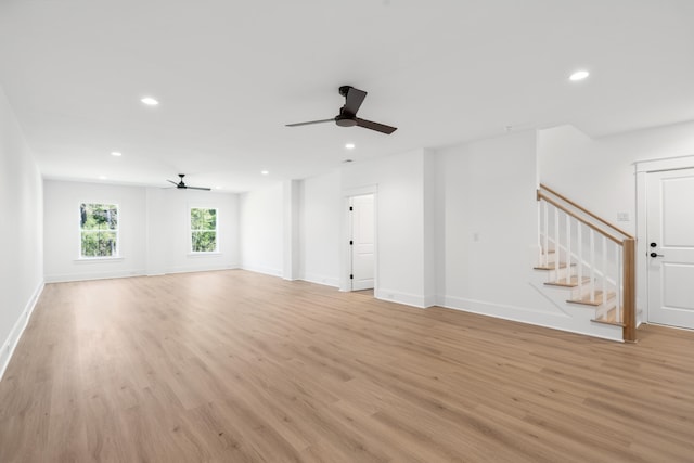 unfurnished living room with recessed lighting, light wood-type flooring, and stairs