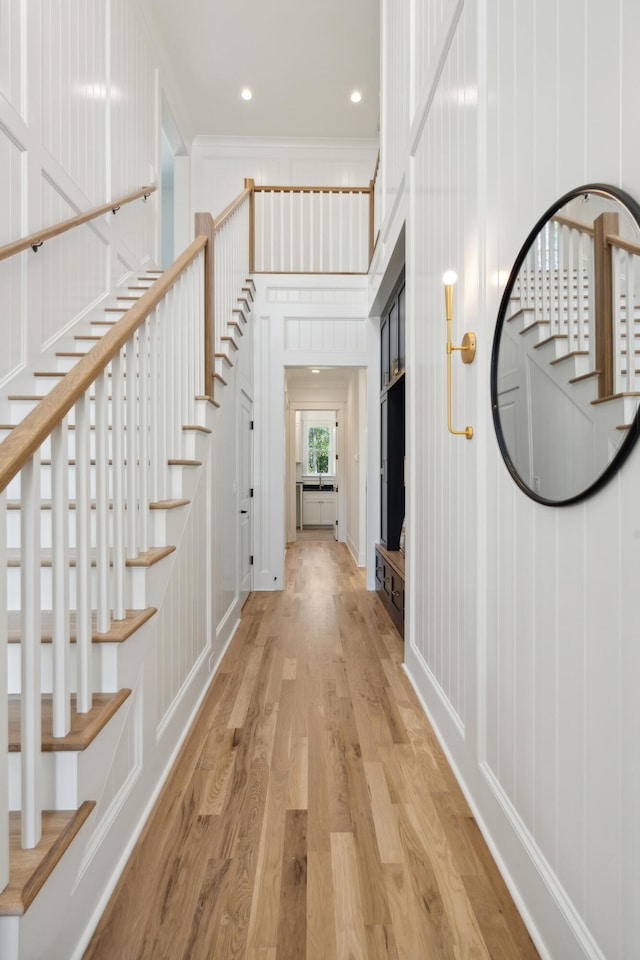 corridor with ornamental molding and light hardwood / wood-style floors