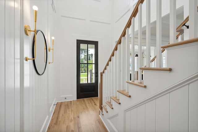 entrance foyer featuring light wood-type flooring, stairway, and a decorative wall