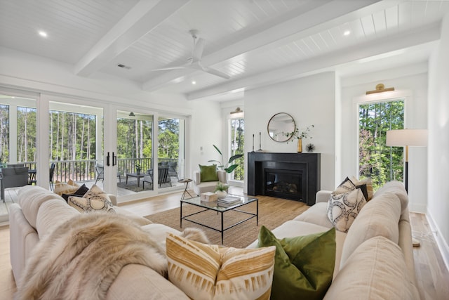 living room featuring a healthy amount of sunlight, light hardwood / wood-style flooring, and beam ceiling