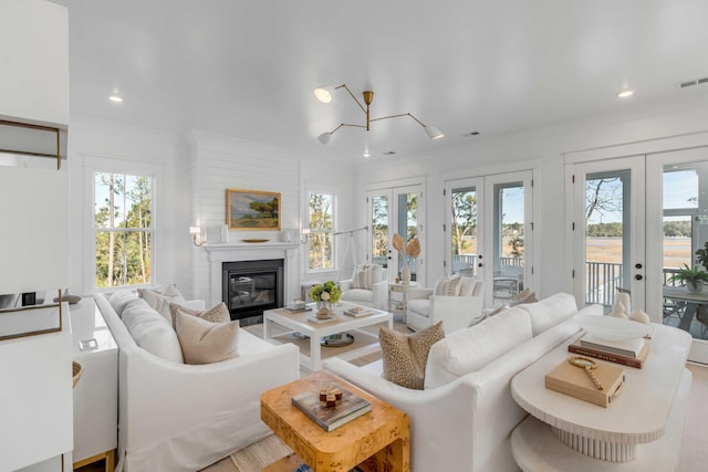 living room featuring french doors, a fireplace, an inviting chandelier, and crown molding