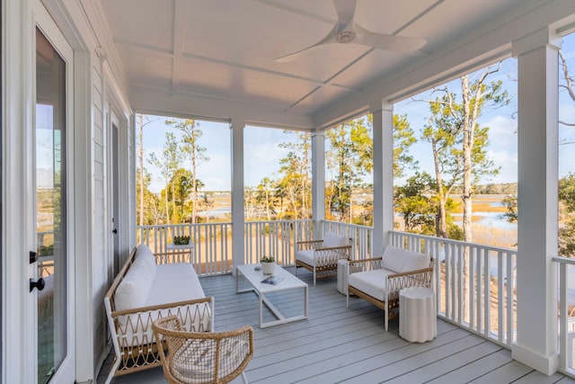 sunroom with ceiling fan and a water view