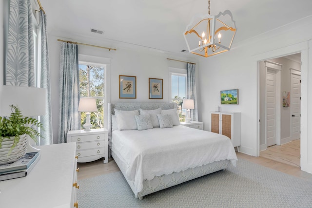 bedroom featuring crown molding, an inviting chandelier, and light wood-type flooring