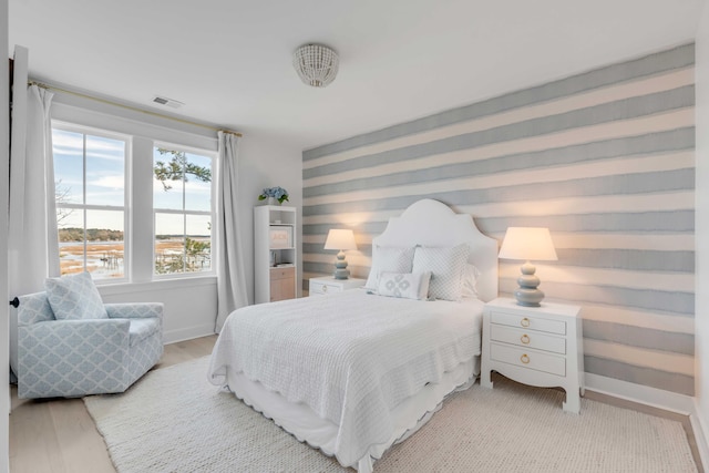 bedroom with a water view and hardwood / wood-style floors