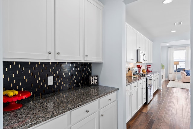 3203 Moonlight Dr, Charleston, SC 29414 - kitchen with appliances with stainless steel finishes, white cabinetry, decorative backsplash, dark wood-style floors, and dark stone countertops