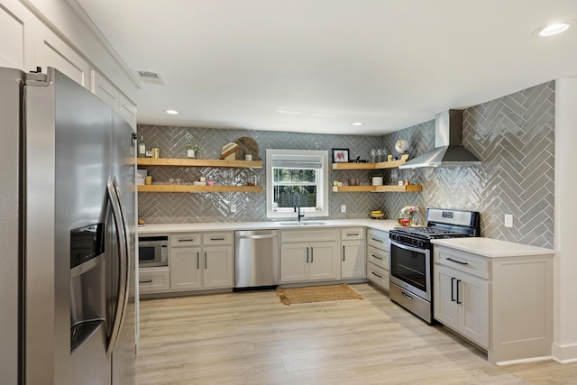 kitchen featuring open shelves, a sink, tasteful backsplash, stainless steel appliances, and wall chimney exhaust hood