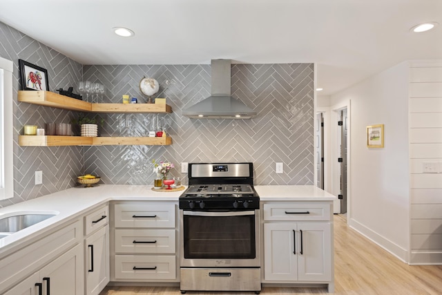 kitchen featuring tasteful backsplash, gas range, light countertops, and wall chimney exhaust hood