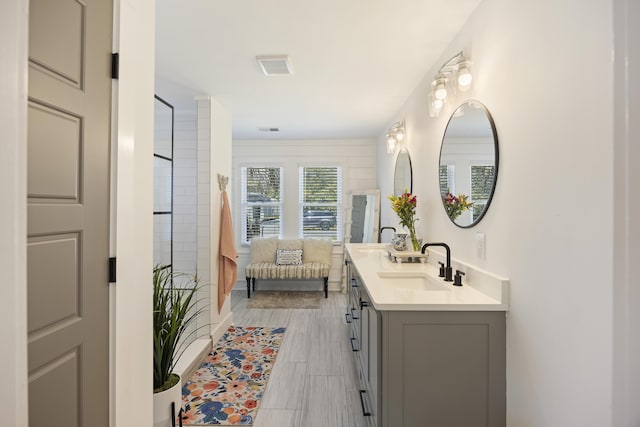 bathroom with ensuite bath, double vanity, visible vents, and a sink