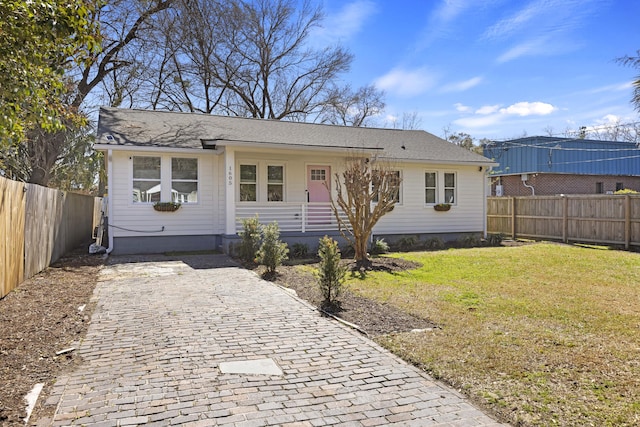 view of front of home with decorative driveway, a front lawn, and fence