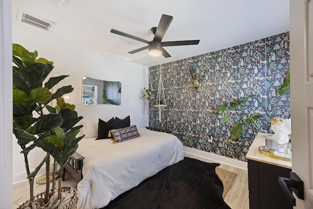 bedroom featuring a ceiling fan, wood finished floors, visible vents, and baseboards