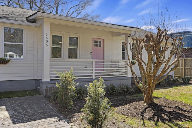 property entrance with covered porch, roof with shingles, and fence