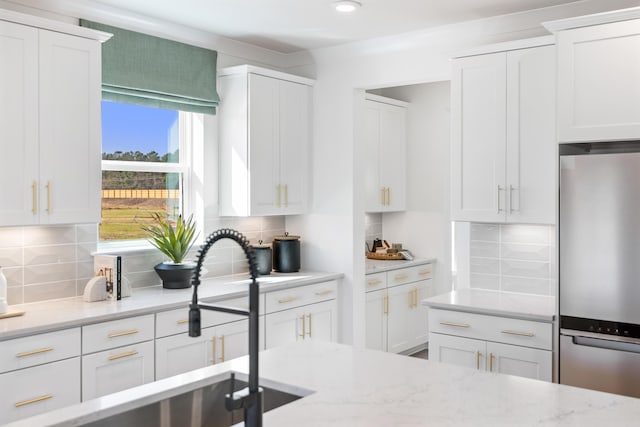 kitchen with white cabinetry, light stone counters, decorative backsplash, and stainless steel refrigerator