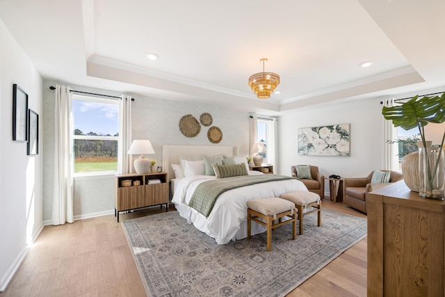 bedroom featuring a chandelier, multiple windows, a raised ceiling, and light hardwood / wood-style flooring