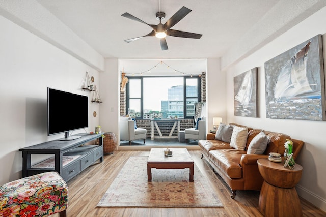 living room featuring a textured ceiling, light hardwood / wood-style floors, and ceiling fan