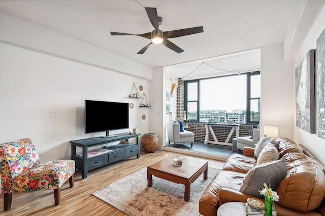 living room featuring a textured ceiling, light wood-type flooring, track lighting, expansive windows, and ceiling fan