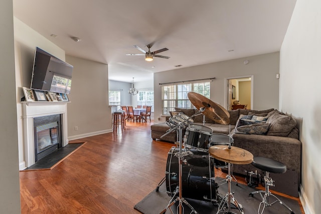 living area featuring visible vents, baseboards, a glass covered fireplace, ceiling fan, and wood finished floors