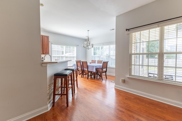 dining space with light wood-style floors, visible vents, a notable chandelier, and baseboards