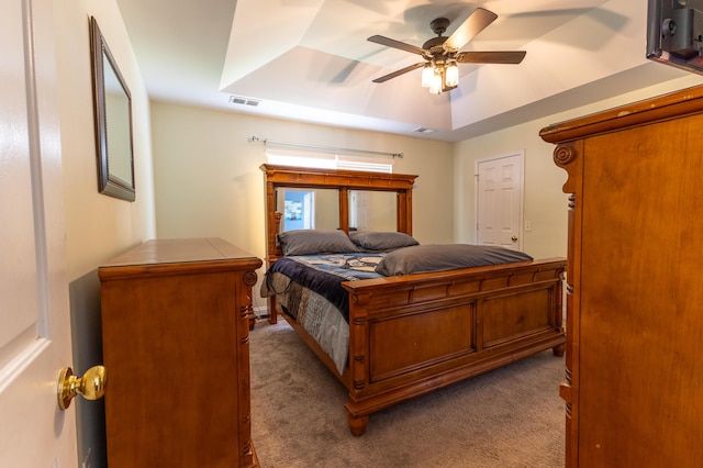 bedroom featuring a ceiling fan, carpet, a raised ceiling, and visible vents