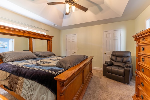 bedroom featuring baseboards, a tray ceiling, ceiling fan, and light colored carpet