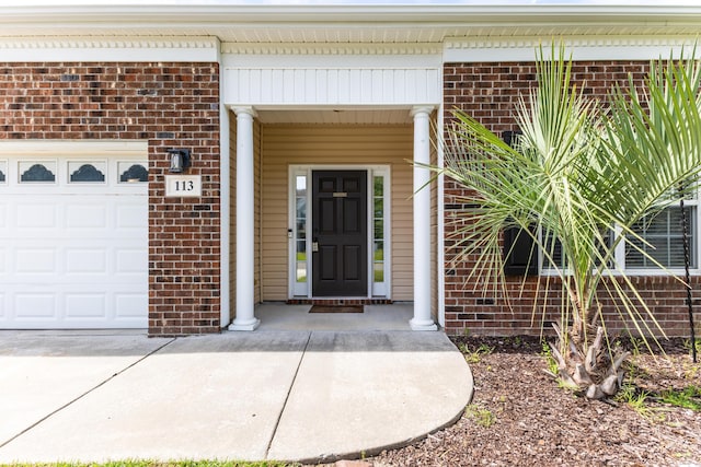 property entrance with brick siding and an attached garage