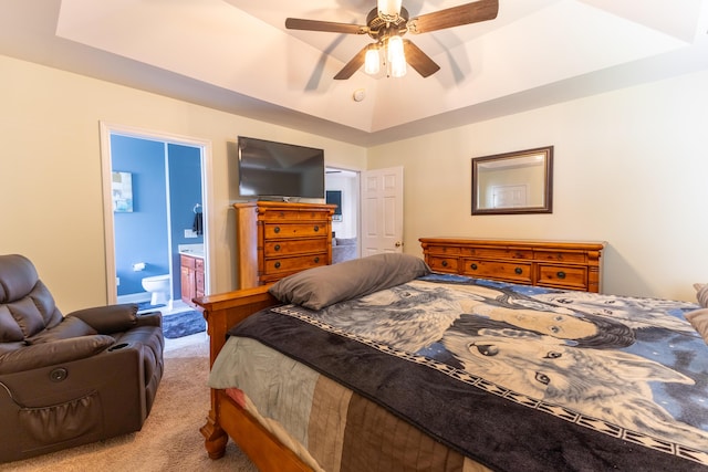 carpeted bedroom featuring ceiling fan, ensuite bath, and a raised ceiling