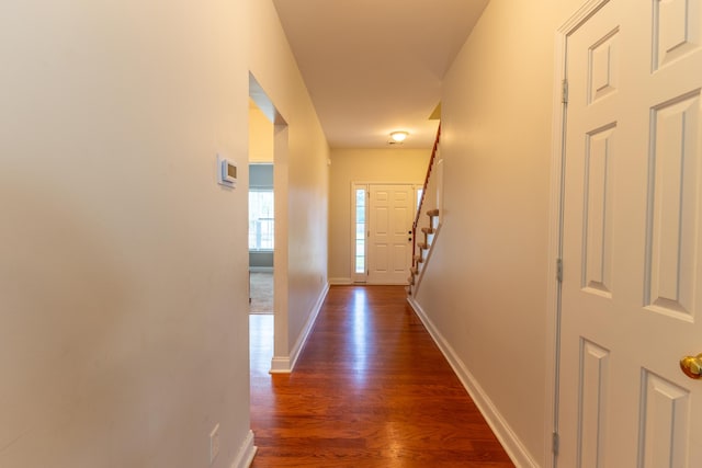 corridor featuring stairs, baseboards, and dark wood finished floors