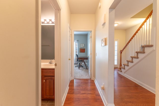 hallway featuring a sink, baseboards, and wood finished floors