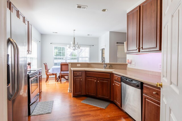 kitchen with a chandelier, dark brown cabinets, dishwasher, dark hardwood / wood-style flooring, and sink