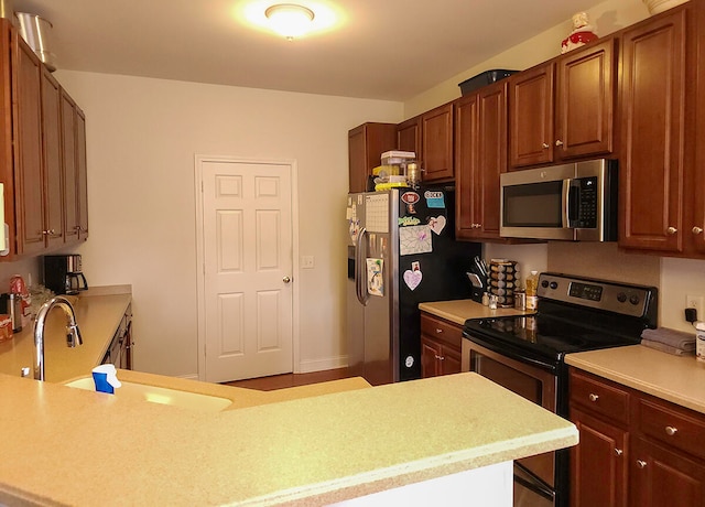 kitchen featuring kitchen peninsula, stainless steel appliances, and sink