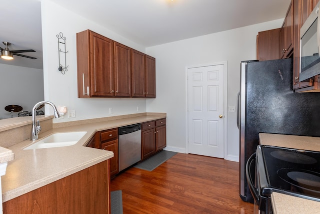 kitchen with dark wood-style flooring, light countertops, appliances with stainless steel finishes, a ceiling fan, and a sink