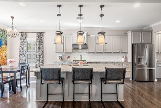 kitchen with dark wood-style flooring, ornamental molding, wall chimney range hood, backsplash, and stainless steel fridge