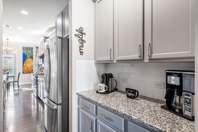 kitchen featuring visible vents, backsplash, appliances with stainless steel finishes, ornamental molding, and dark wood-type flooring