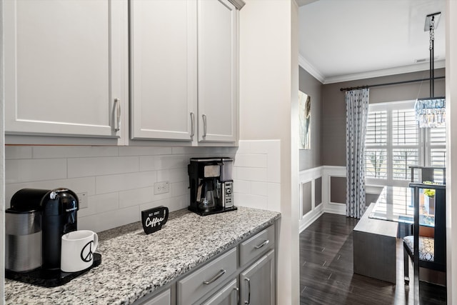 kitchen with decorative backsplash, light stone counters, dark wood-type flooring, crown molding, and gray cabinetry