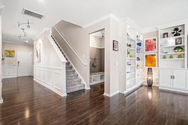 interior space with dark wood-style flooring, rail lighting, visible vents, ornamental molding, and stairs