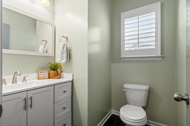 bathroom featuring toilet, baseboards, and vanity