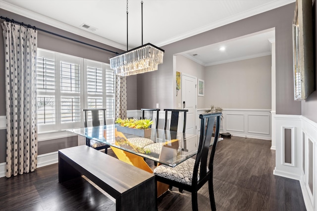 dining room featuring a wainscoted wall, crown molding, dark wood finished floors, visible vents, and a decorative wall