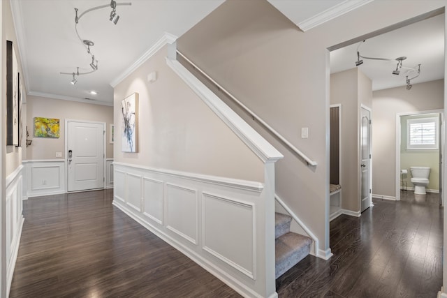 foyer entrance featuring crown molding, rail lighting, dark wood finished floors, and stairway